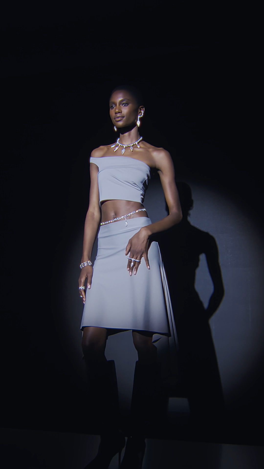 Model posing against a black background, wearing Messika creations