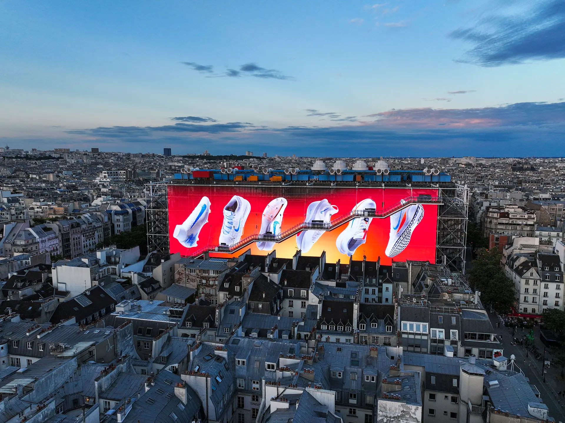 NIKE shoes displayed on a colorful background on the giant screen, in front of the Centre Pompidou