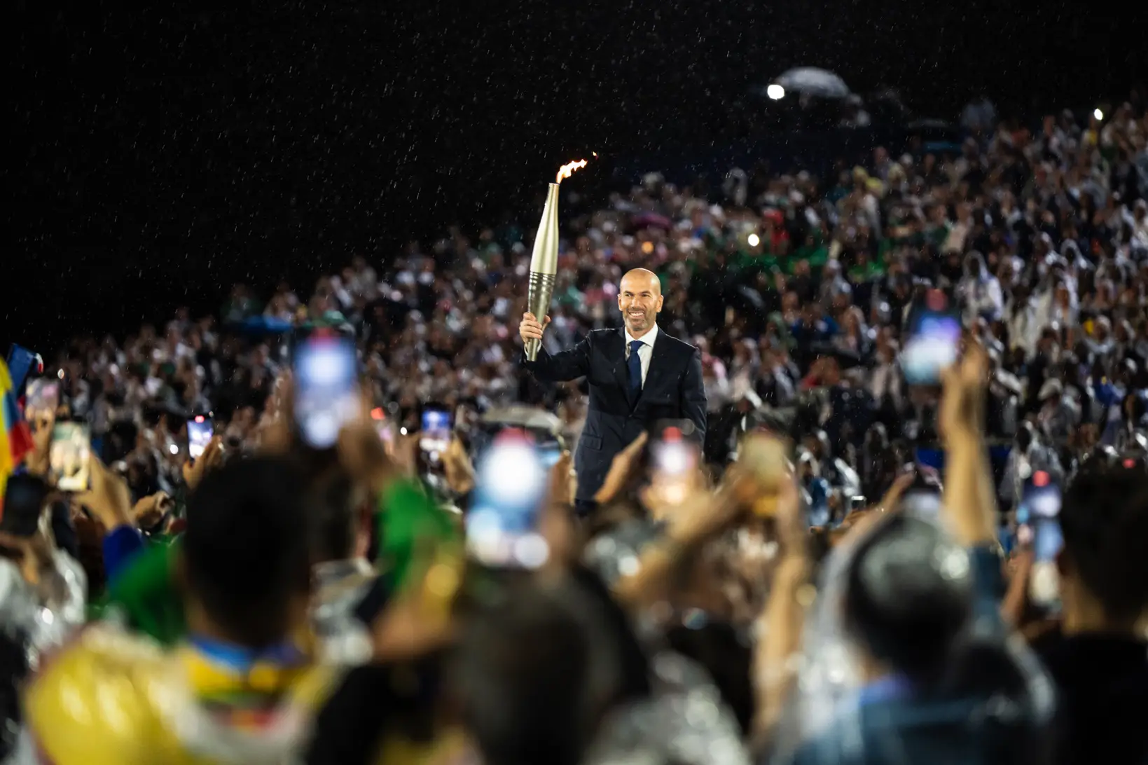 Zinedine Zidane holding the Olympic Torch among the crowd