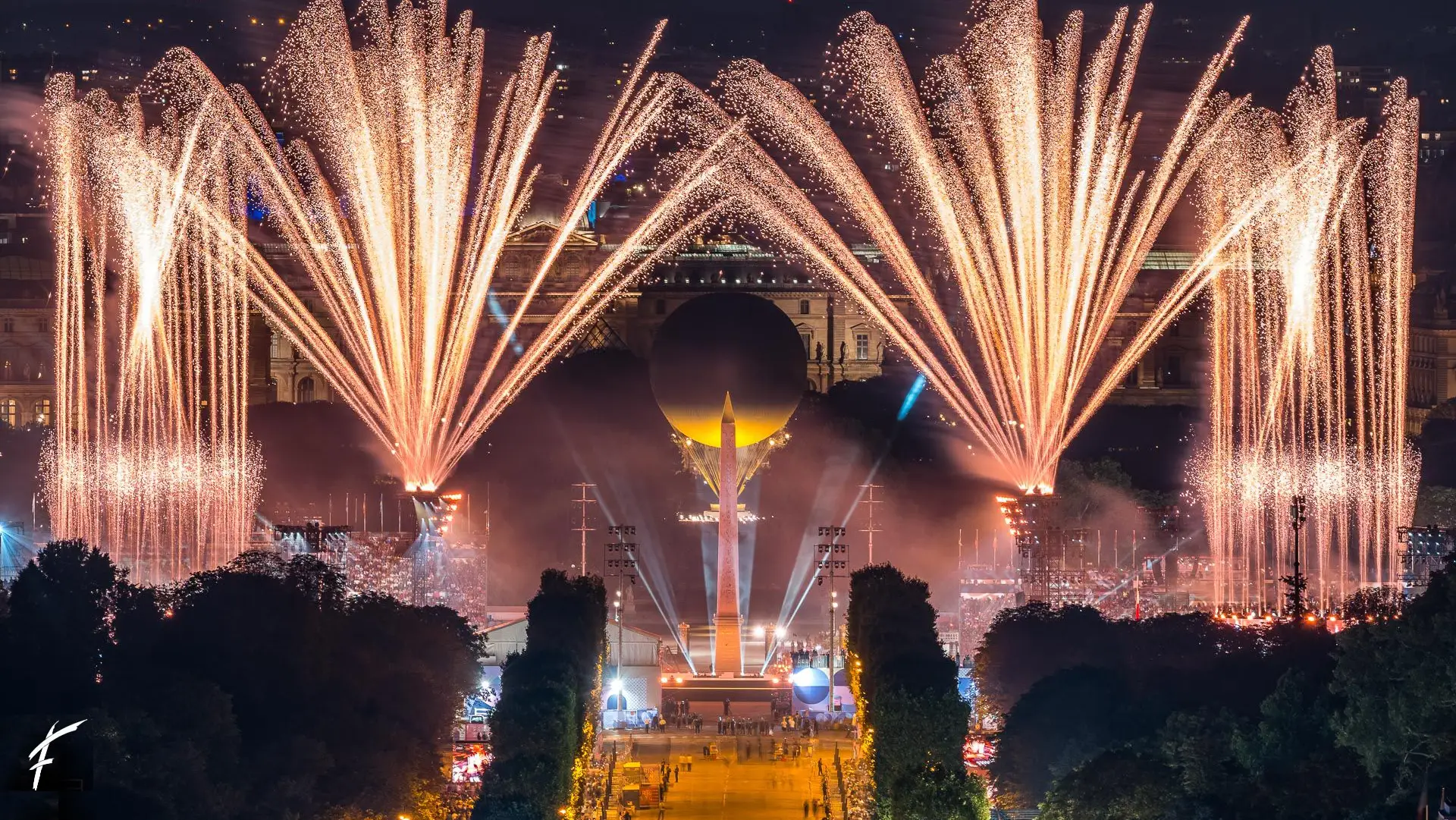 Fireworks over the place de la Concorde in Paris, olympic cauldron in the background
