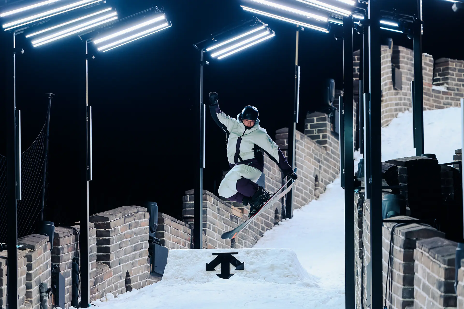 Great Wall covered by snow, an athlete jumps over the snow and does a pose with his ski pair for DESCENTE