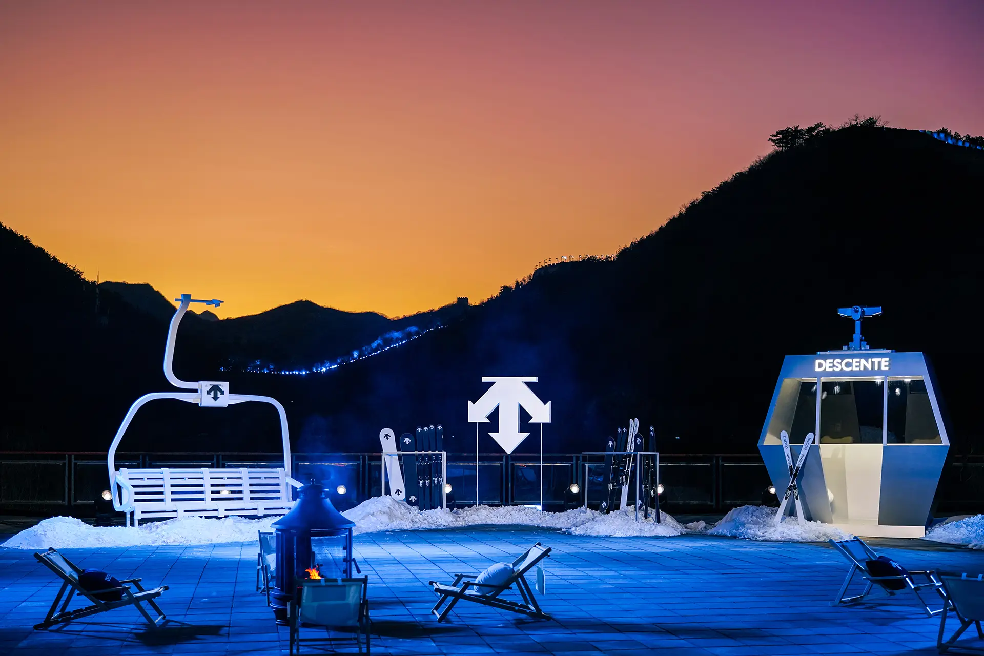 Ski station by DESCENTE, winter sports equipment on display, mountain skyline in the background, dusk, Great Wall